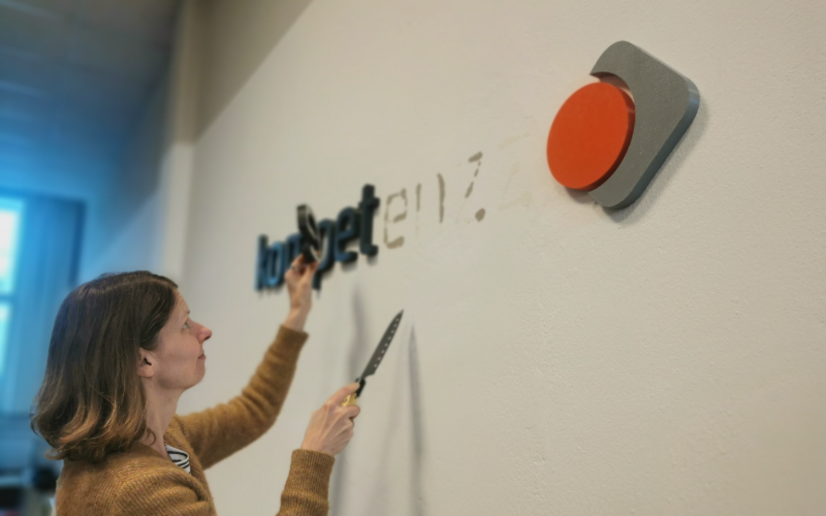 Eine Mitarbeiterin von kompetenzz entfernt die Buchstaben des Vereinsnamens von der Wand.