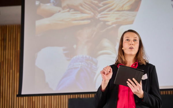 Christiane Knirsch steht auf einer Bühne und hält einen Vortrag.