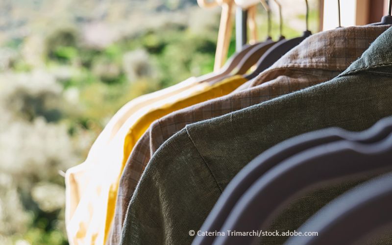 Verschiedene Hemden auf Kleiderbügeln vor einem grünen Berg