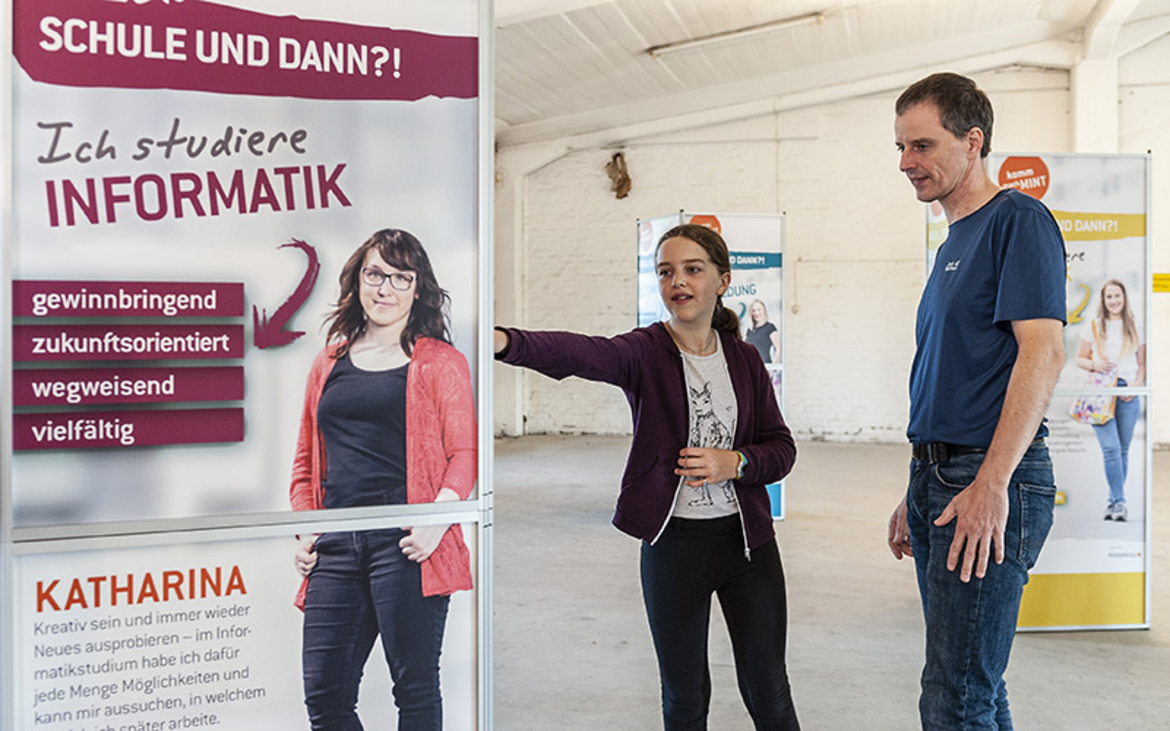 Vater und Tochter stehen neben einer Stele der Wanderausstellung