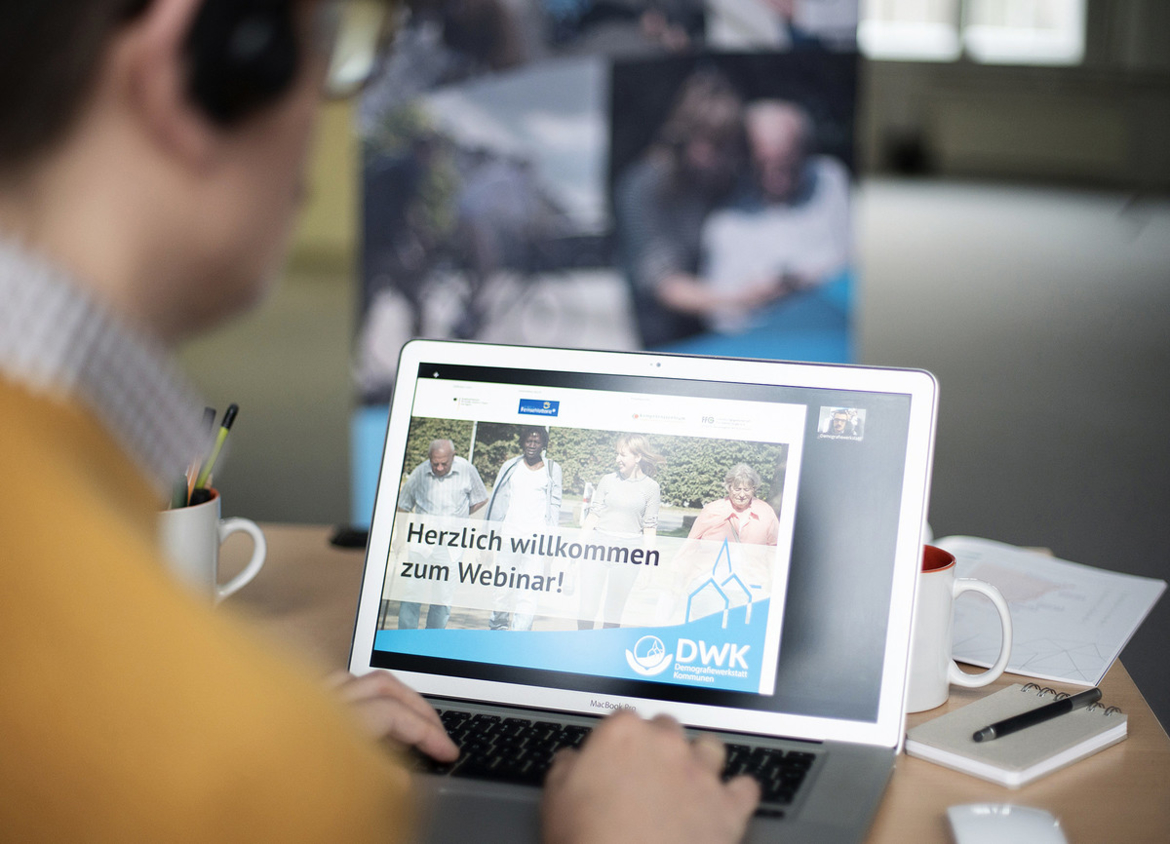 Online-Seminare DWK Eine Person sitzt mit Kopfhörern vor einem Laptop, auf dem ein Online-Seminar stattfindet.