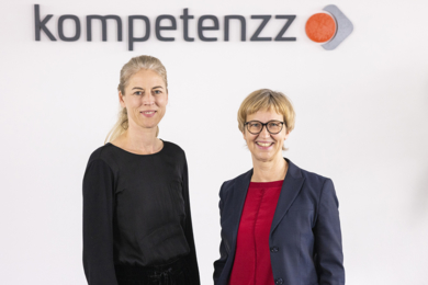 Foto von den Geschäftsführerinnen Romy Stühmeier und Sabine Mellies mit einem kompetenzz-Logo im Hintergrund
